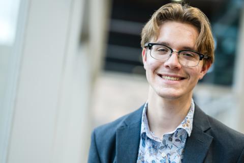 Niko Jones smiling at the camera wearing a suit